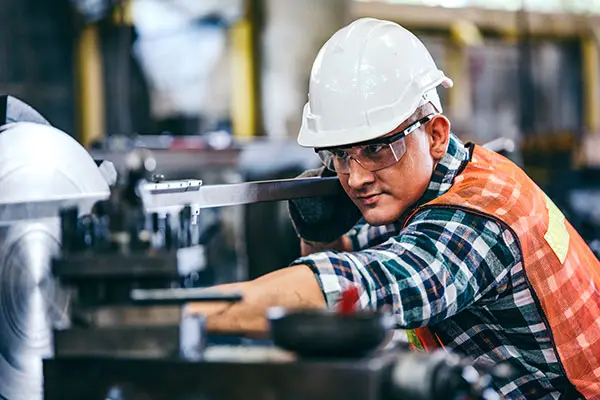 Male engineer metalworker industrial experienced operator technician worker in safety hard helmet working on lathe machine, professional man in industry technology manufacturing factory workshop