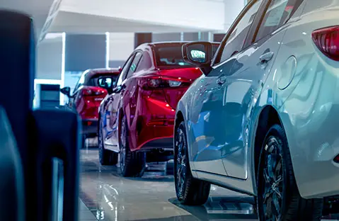 Rear view of new luxury red and white car parked in modern show room. Selective focus on white shiny car. Car dealership concept. Showroom interior. Automotive industry on coronavirus crisis concept.