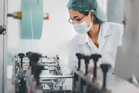 Asian female doctor or engineer working at clean medical mask production factory